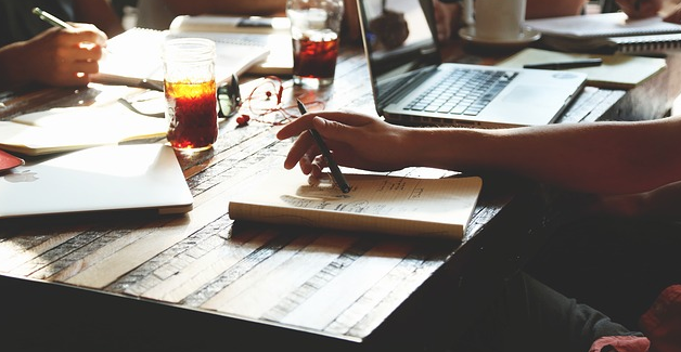 Writing code at a desk with laptop and notepad
